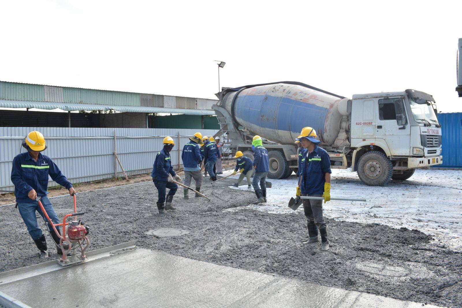Workers placing and leveling fresh concrete on a job site (stock photo)