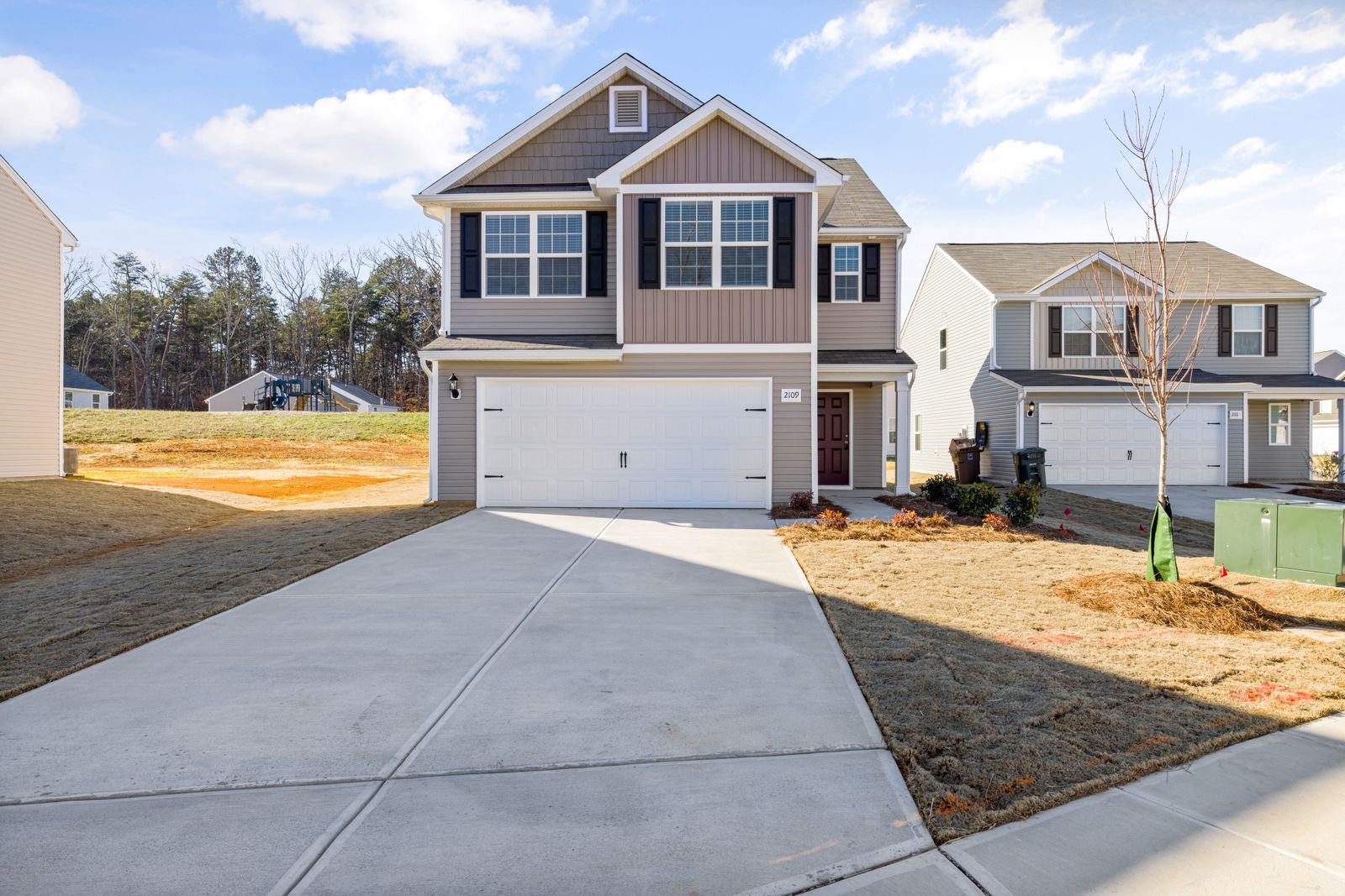 Two-story house with a wide concrete driveway (stock photo)